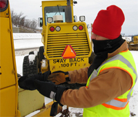 worker dressed for the cold in a jacket, scarf, hat, and gloves