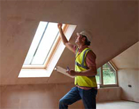 Photo shows worker inspecting a skylight following installation.