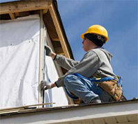 Photo shows worker checking an outside corner for plumb on a building site.