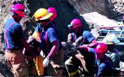 A fire department rescue team helps a worker to safety after a trench cave-in.