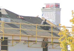 Figure 10 - An exterior bracket scaffold with guardrails being used to protect workers while weatherproofing.