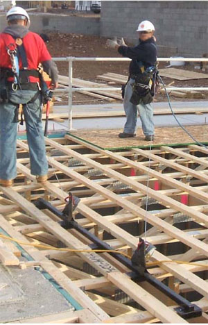 Figure 20 - Workers using a truss bracket anchor while installing a subfloor.
