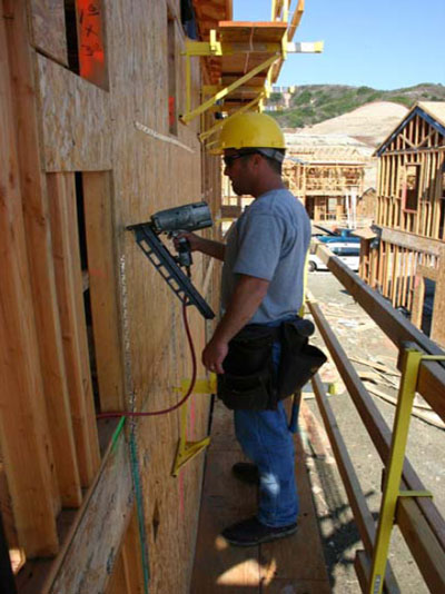 Figure 29 – A worker sheathing walls from an exterior bracket scaffold.