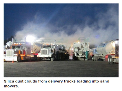 Silica dust clouds from delivery trucks loading into sand movers.