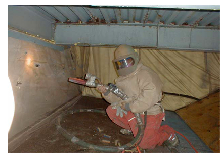 Photo of worker using abrasive blasting on a wall.