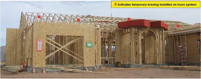 Photo 1: House in frame just after trusses erected and set. Stack of OSB above entryway to the right was being put into position when worker fell.