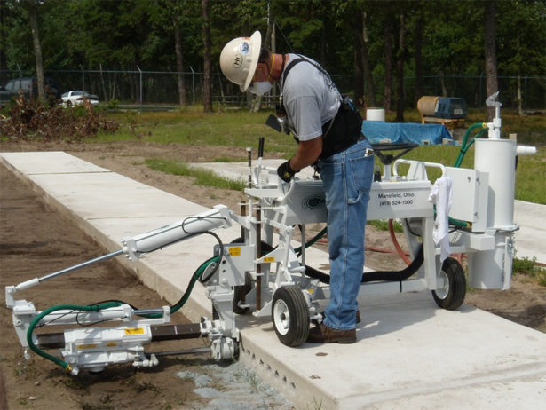 photo of a man operating a slab-riding, single-drill dowel drilling machine