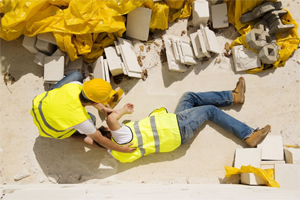 Photo of a construciton worker lying on the ground with another aiding him.