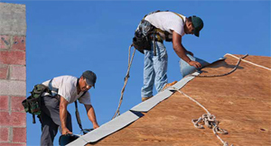 Photo shows roofers applying felt on top of roof sheathing