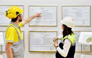 Photo shows two workers in a training room reviewing an operating procedure.