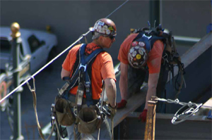 Photo shows workers at height securing steel beams together