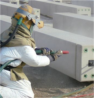 Fully protected person with PPE equipped with helmet, air filtration gloves, coveralls, apron, while abrasive blasting