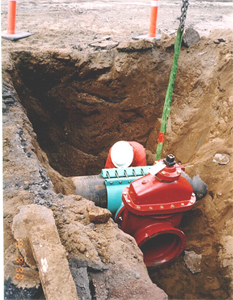 worker tending to a pipe in a trench