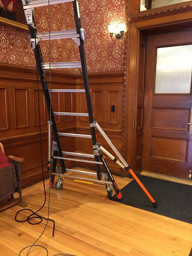 photo of platform ladder with one wheel lift assembly engaged and one outrigger deployed