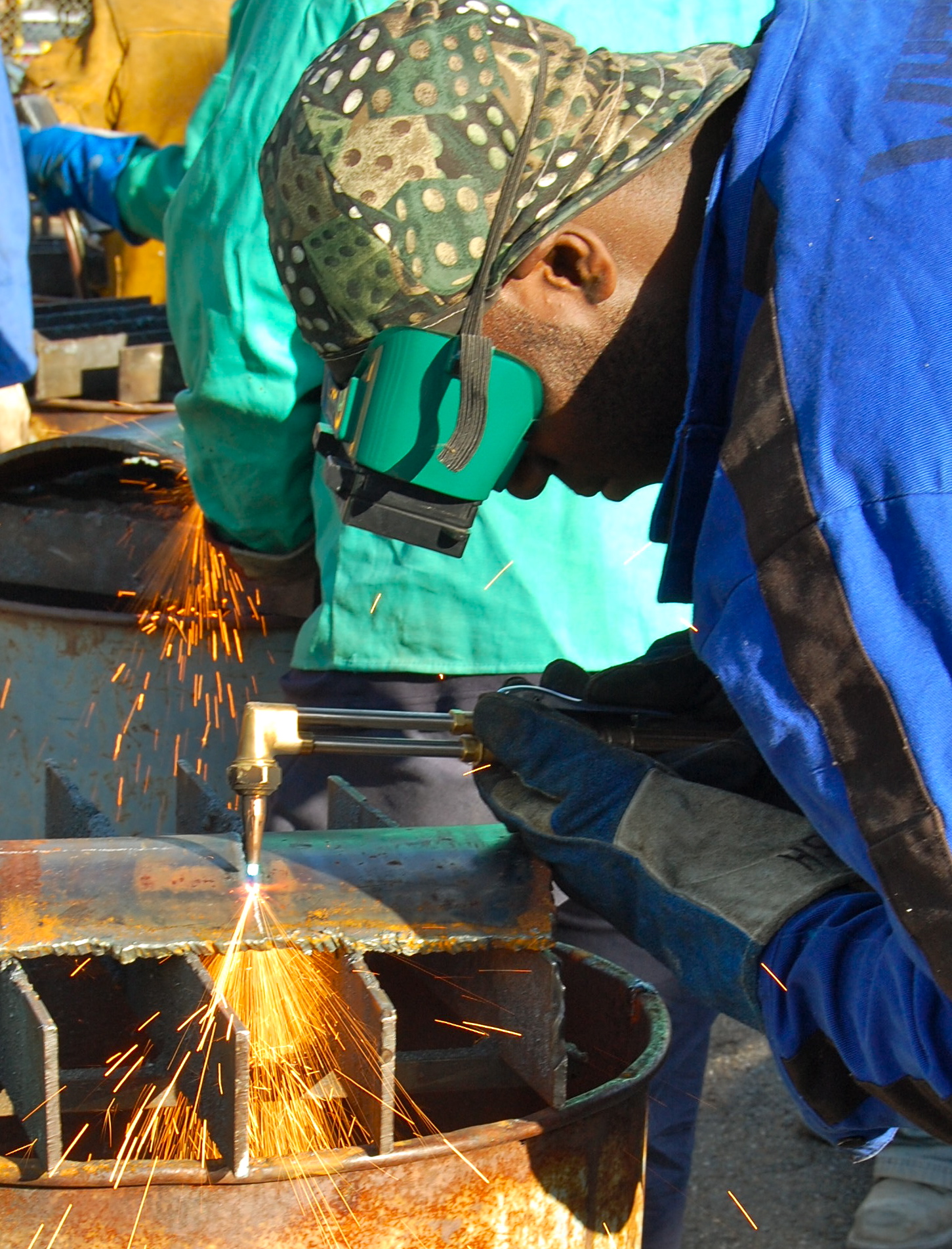 Cutting metal with oxyacetylene torch wearing protective gloves